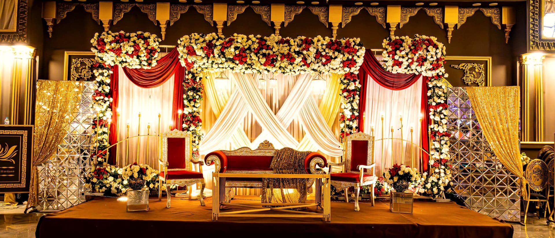 Wedding stage dressed in florals and drapery, lit for the ceremony