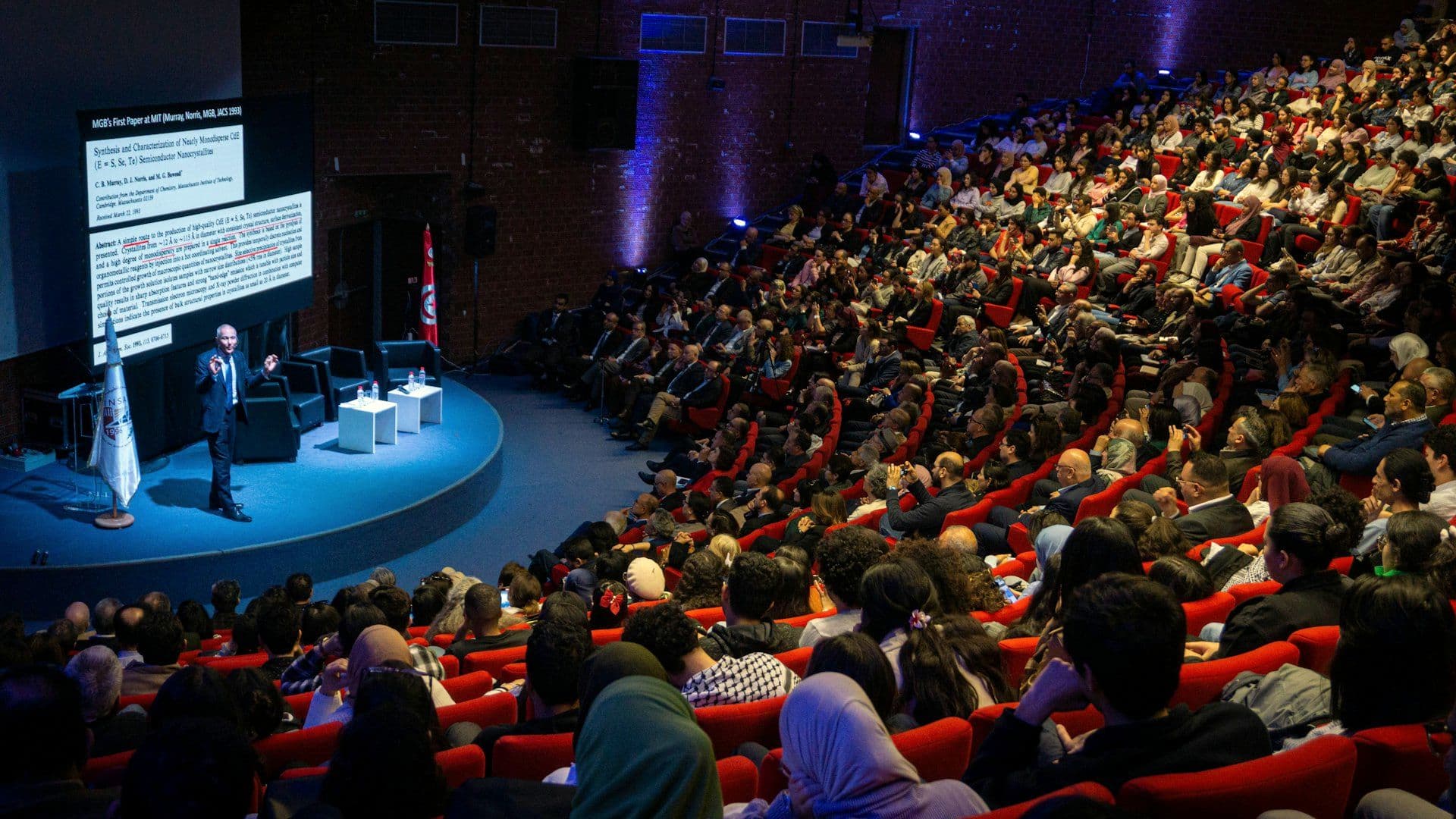 Speaker addressing a full auditorium at a conference