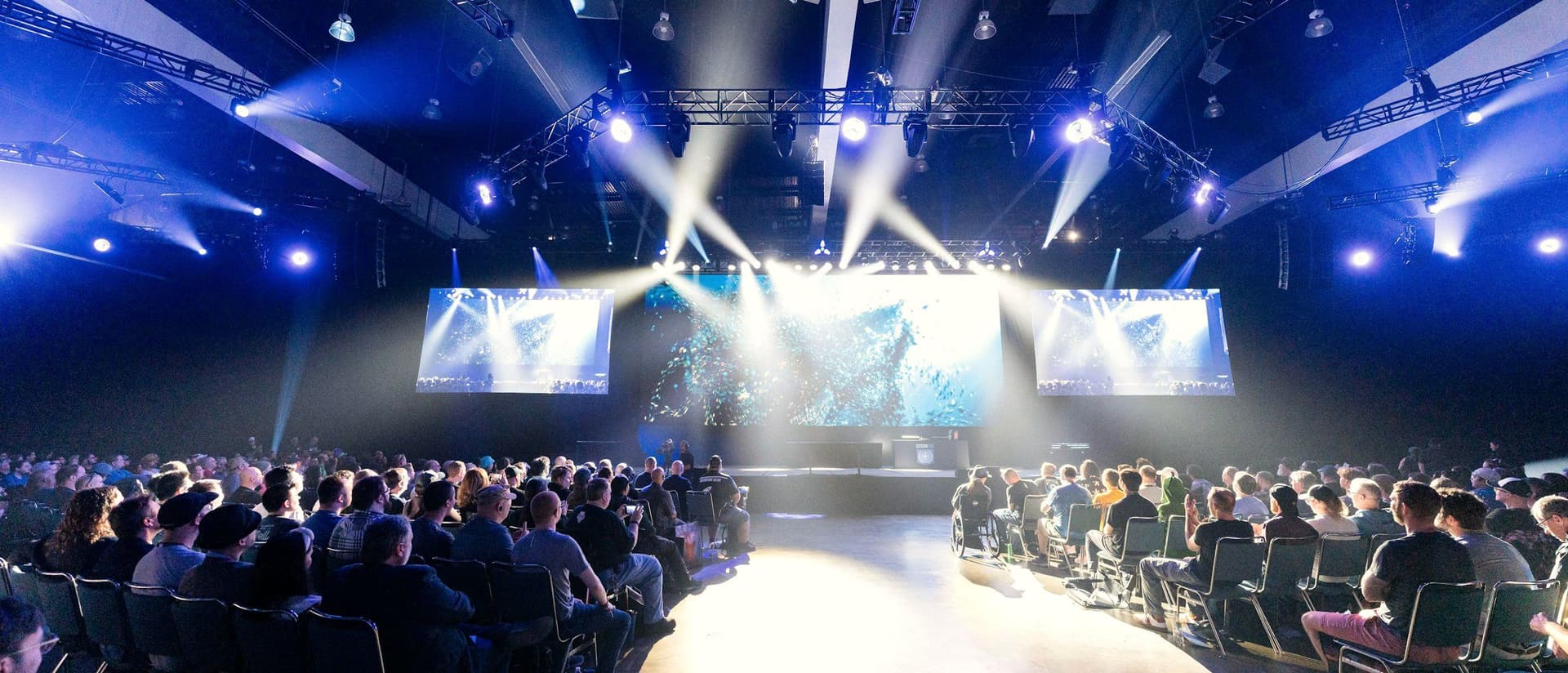Audience seated before a lit stage at a corporate production