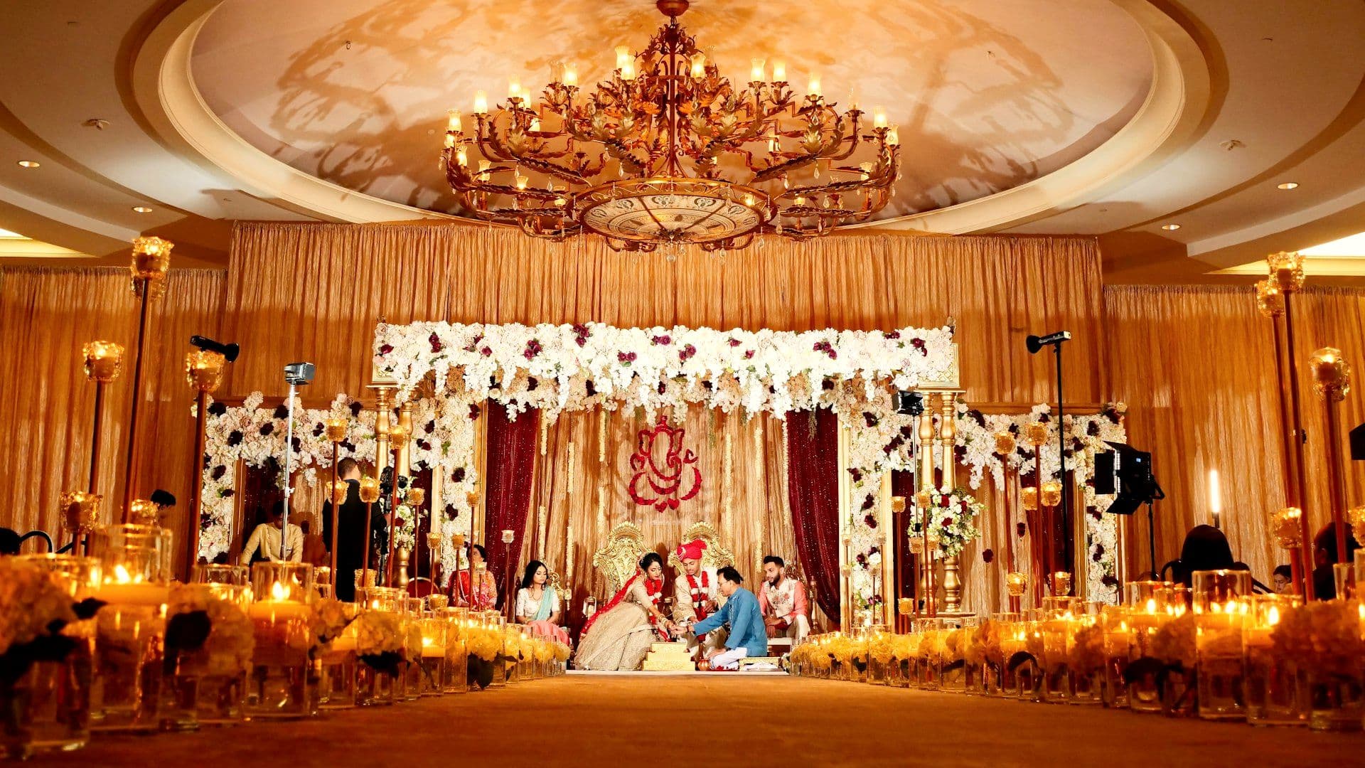 Couple seated beneath a floral mandap during the ceremony