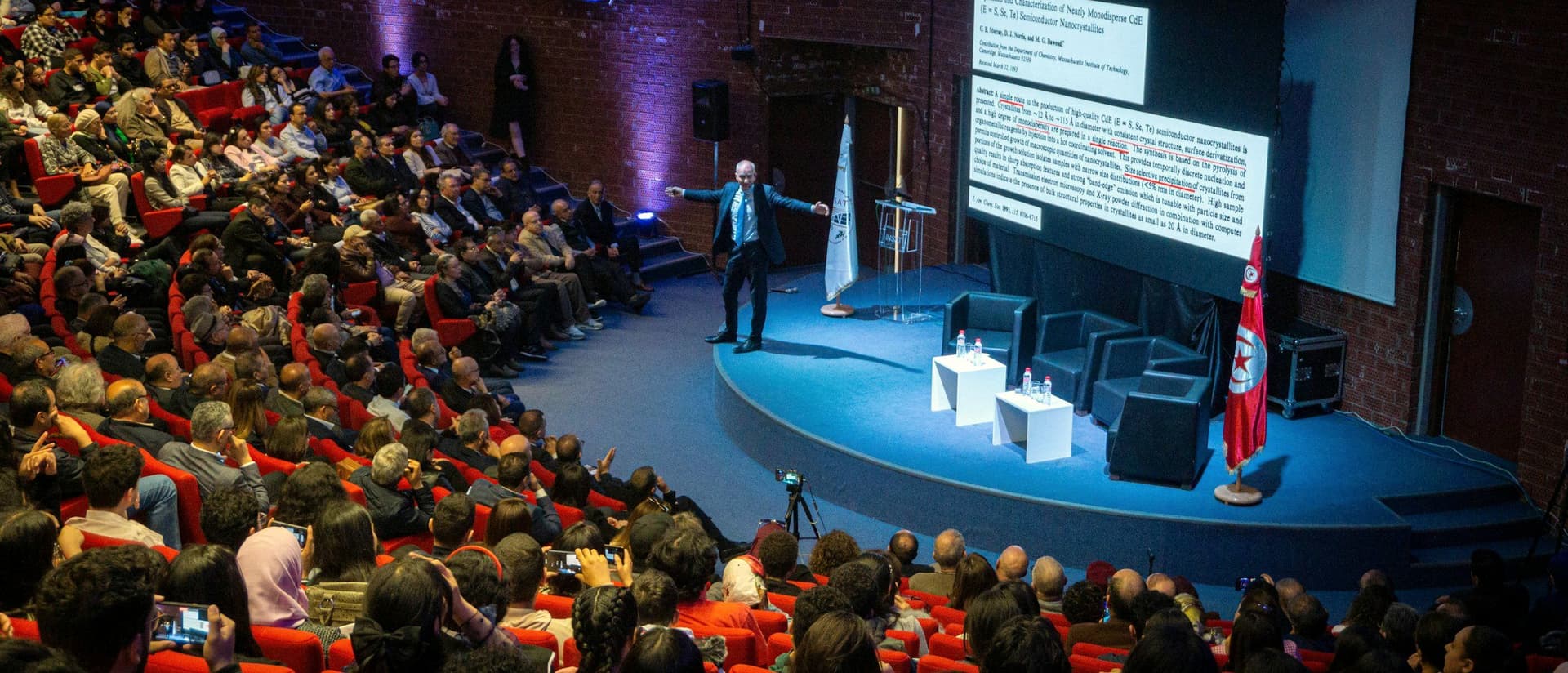 Speaker presenting to a large delegate audience in a conference hall