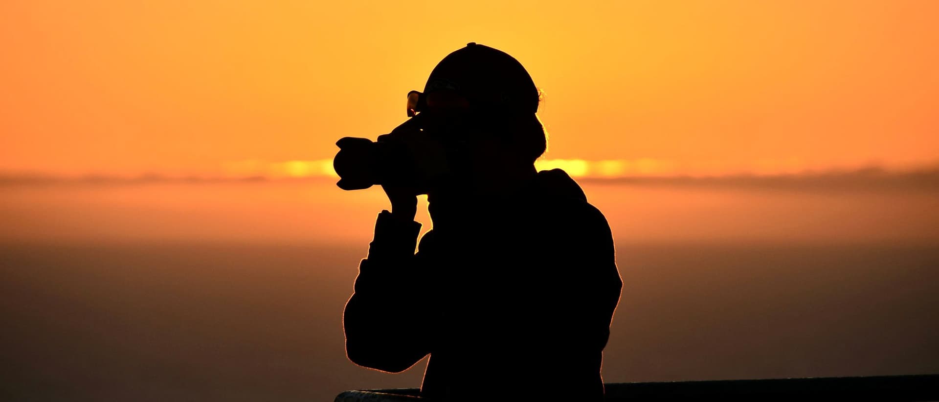 Photographer silhouetted while shooting at golden hour