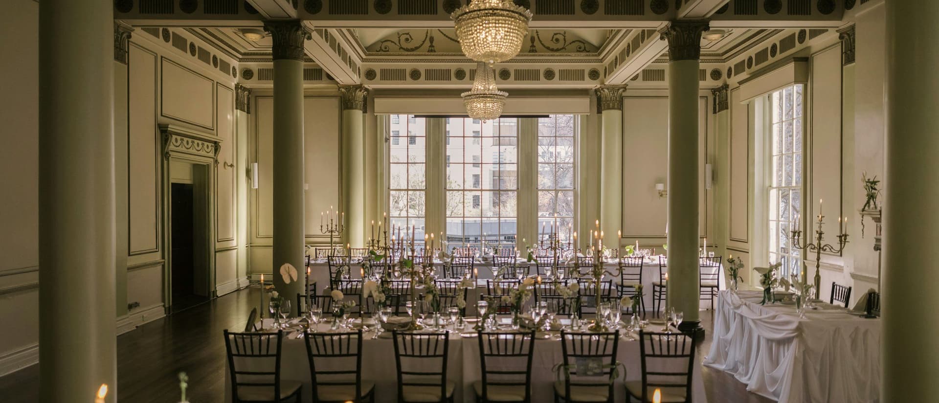 Ballroom laid with long tables beneath chandeliers